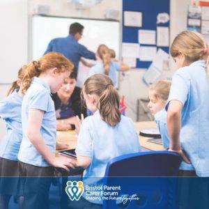 Primary aged children in class standing at desk