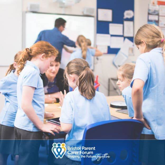Primary aged children in class standing at desk