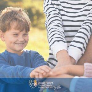 A smiling young boy outdoors joins hands with an adult and others in a supportive group gesture, representing community, care, and togetherness.